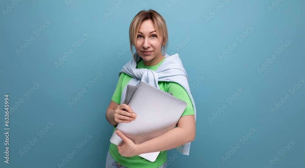 blond attractive business lady in a casual look with a laptop in her hands on a blue background blond attractive business lady in a casual look with a laptop in her hands on a blue background