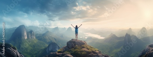 Woman standing on top of the mountain with arms outstretched against the mountain scenery