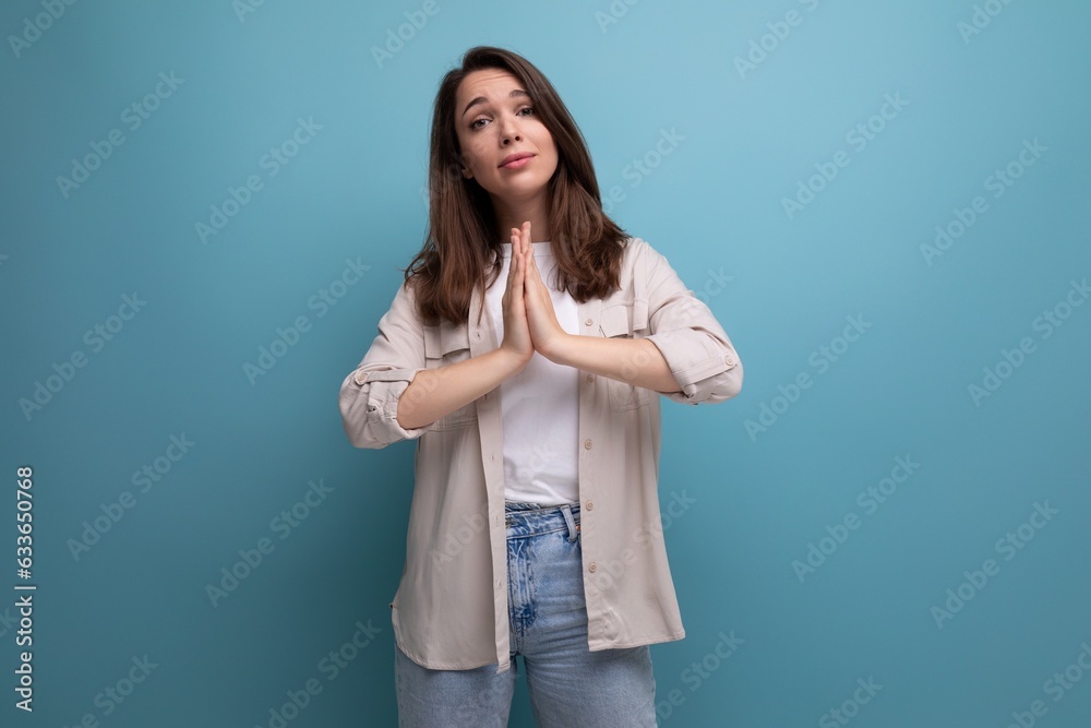 European model appearance young dark-haired lady in informal clothes posing against a blue background European model appearance young dark-haired lady in informal clothes posing against a blue background