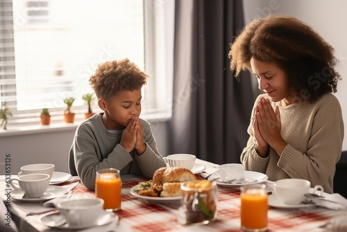 Happy multiracial family couple with children pray together before having morning breakfast at home together. Multiethnic parents with mixed race kids hold hands say prayer sit at kitchen table