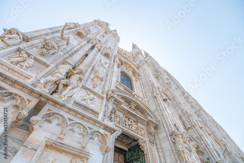 Milan Cathedral, Italian: Duomo di Milano, or Metropolitan Cathedral-Basilica of the Nativity of Saint Mary. View of main door and white marble facade on sunny summer day. Milan, Lombardy, Italy photo