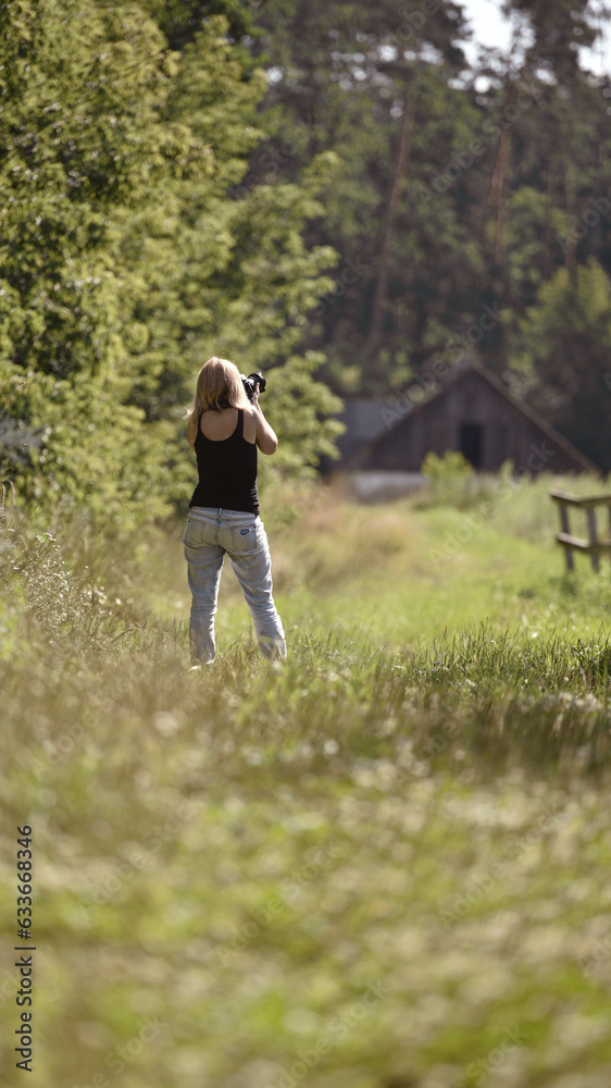 girl photographer photographing nature, walking in the woods, back view. young woman in spring forest. girl tourist. enjoying spring weather. Rest, lifestyle, walk in the fresh air. hiking in nature girl photographer photographing nature, walking in the woods, back view. young woman in spring forest. girl tourist. enjoying spring weather. Rest, lifestyle, walk in the fresh air. hiking in nature