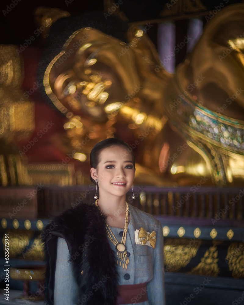 A beautiful pretty Asian Thai woman wearing modern traditional Thai dress clothes posted at ancient temples in Chiang Mai Thailand.