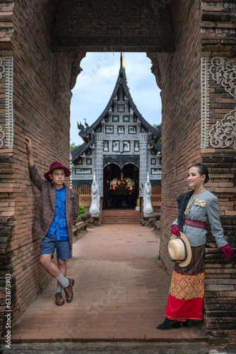 A beautiful pretty Asian Thai woman and handsome man wearing modern traditional Thai dress clothes posted at ancient temples in Chiang Mai Thailand. © pomphotothailand