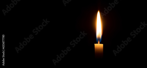 Fotografia Single burning candle flame or light glowing on a small white candle on black or dark background on table in church for Christmas, funeral or memorial service with copy space