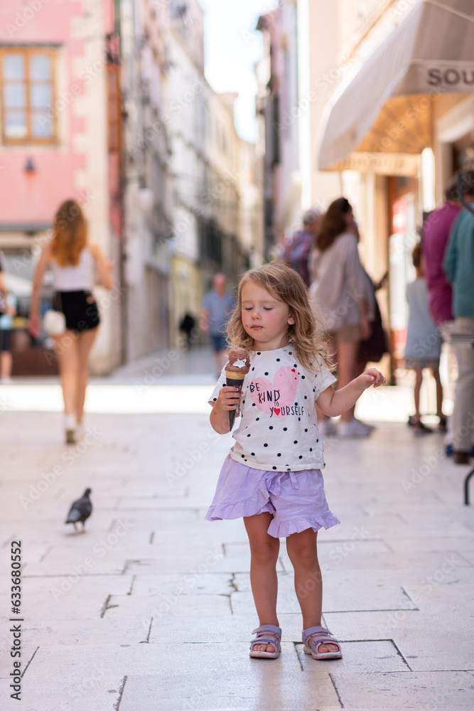 Beautiful Caucasian girl with ice cream on the street of an ancient city in Croatia