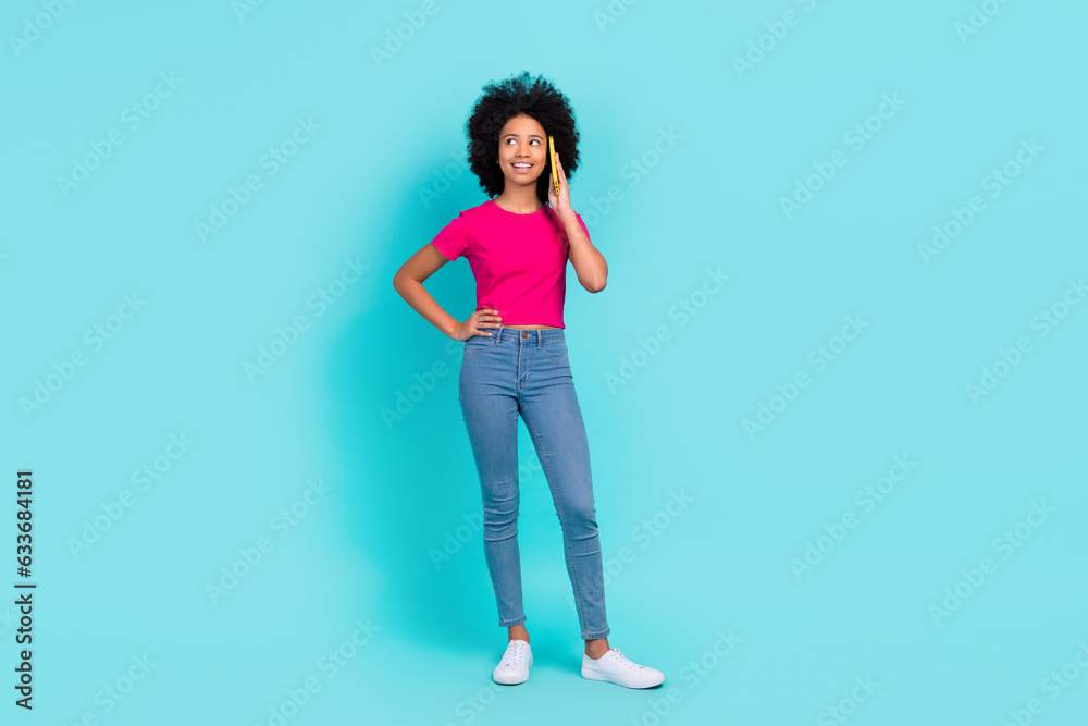 Full size portrait of small positive charming girl speak communicate telephone empty space isolated on turquoise color background Full size portrait of small positive charming girl speak communicate telephone empty space isolated on turquoise color background
