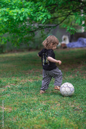 Little boy playing football on the grass