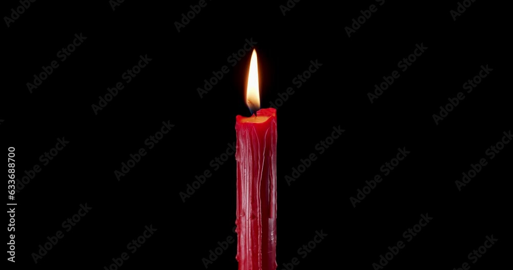 A single red candle burning. Isolated candle burning with dark background. Red paraffin candle with yellow shades burns on a black background. Background or illustration of remembrance or celebration. A single red candle burning. Isolated candle burning with dark background. Red paraffin candle with yellow shades burns on a black background. Background or illustration of remembrance or celebration.