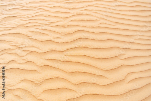 Close up photo of texture of desert sand dunes. Beautiful structures of sandy dunes on sunny summer day. Golden sand of desert. 