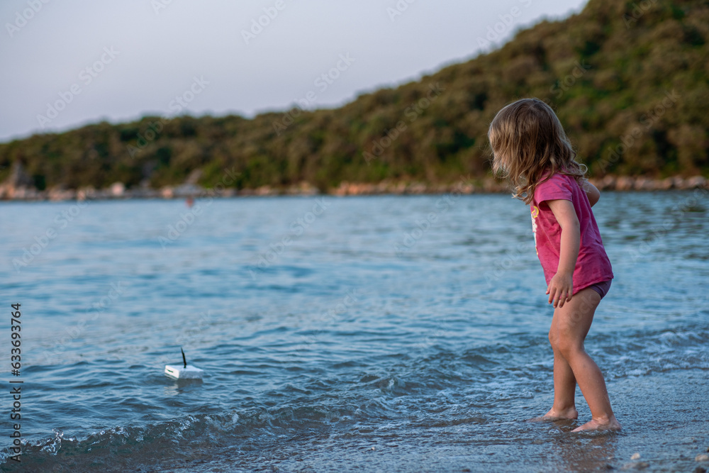 Little girl playing on the sea sandy beach. A girl in a pink t-shirt and swimming trunks on a beautiful sea beach. Cleanest tranquise water of Adriatic sea. Little girl playing on the sea sandy beach. A girl in a pink t-shirt and swimming trunks on a beautiful sea beach. Cleanest tranquise water of Adriatic sea.