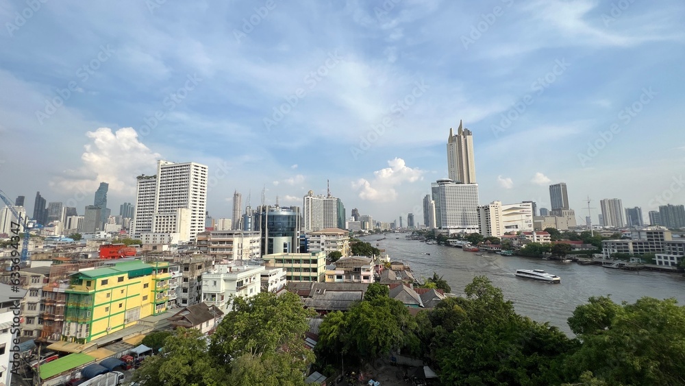 Obraz premium Skyscrapers along Chao Praya river, boat traffic on the river.