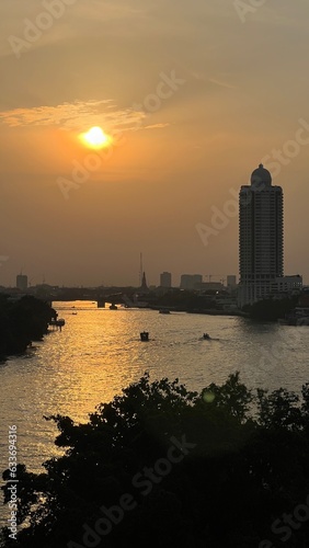 Aerial view of boat traffic on Chao Praya river with sunset, skyscrapers along Chao Praya river during sunset.