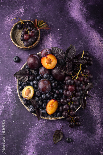 Assortment of purple fruit plum, grape, blueberry and basil