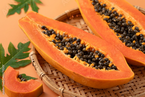 Fresh tropical cut papaya fruit over orange table background. photo