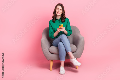 Full length photo of minded lovely person sit cozy chair use smart phone look empty space isolated on pink color background