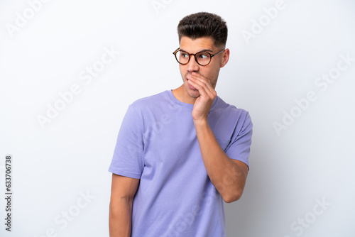 Young caucasian man isolated on white background whispering something with surprise gesture while looking to the side
