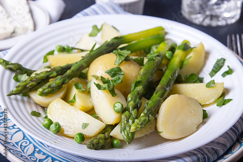 Boiled potato with grilled green asparagus on blue plate over on deep dark background. Overhead.