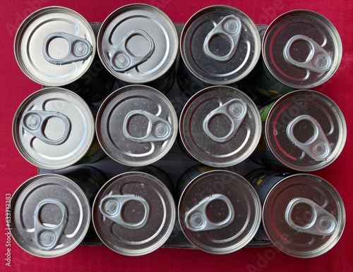 arranged tin cans with opener from above with red background