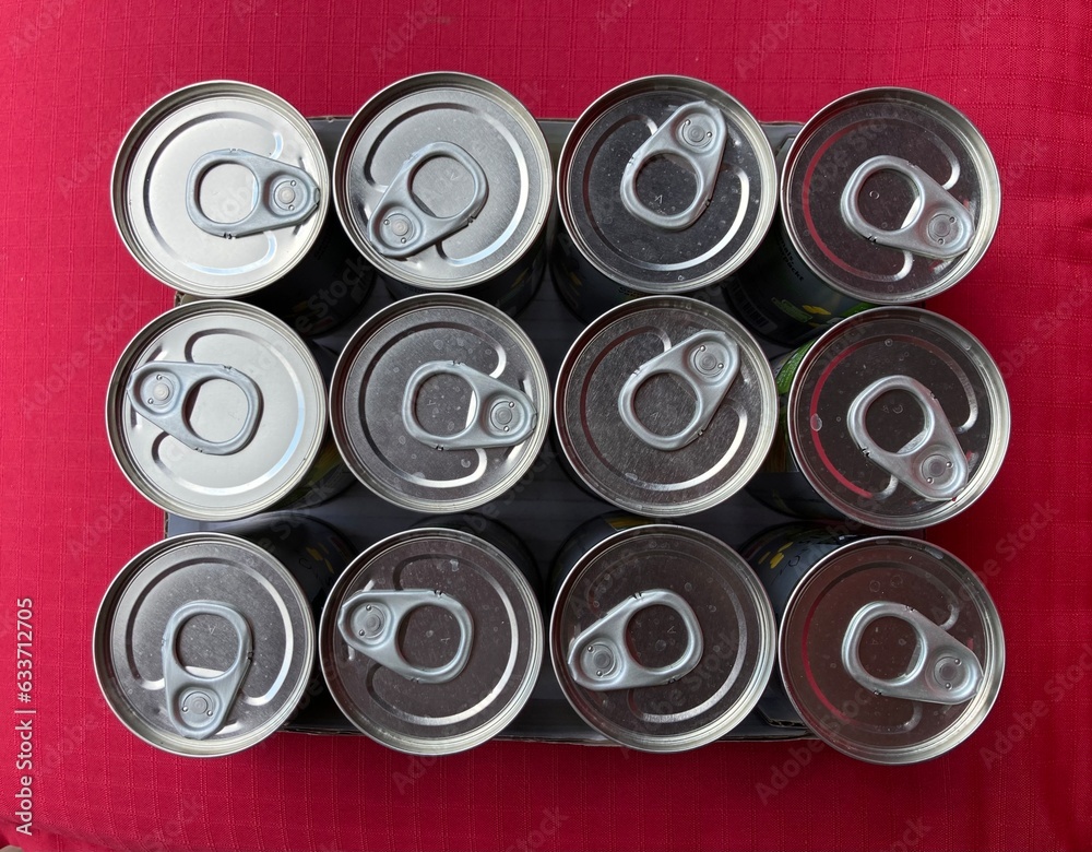 arranged tin cans with opener from above with red background arranged tin cans with opener from above with red background