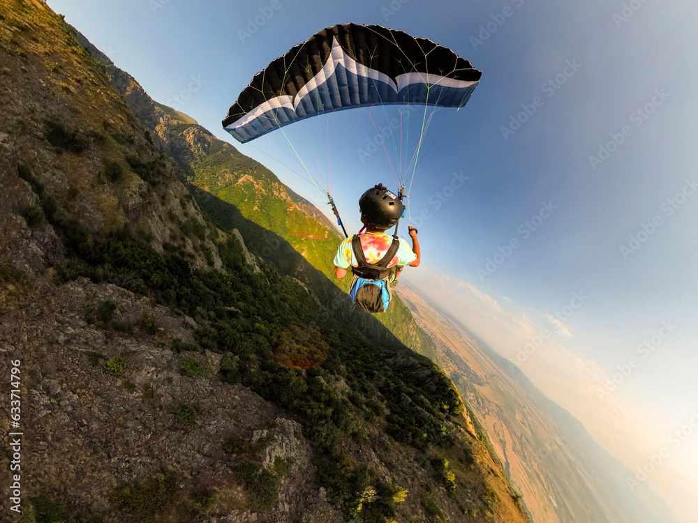 Fototapeta premium Extreme paraglider pilot flying over Bulgarian mountains, adventure concept.