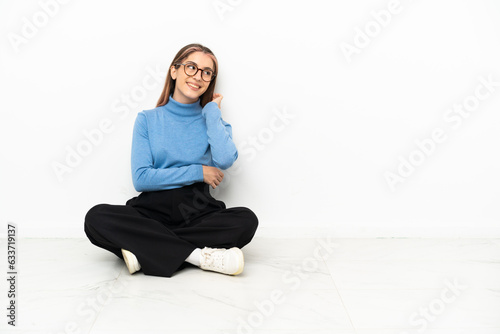 Young Caucasian woman sitting on the floor thinking an idea