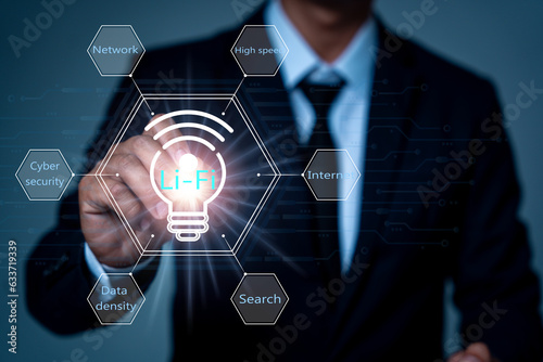 An IT businessman in a black suit touches the Lifi symbol in a hexagonal grid surrounded by words related to a topic, such as information search. high-speed internet communication cyber security photo