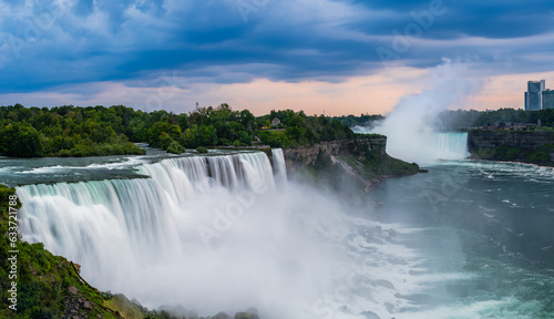 A panoramic long exposure photo of the American - Canadian waterfalls Niagara Falls in cloudy dusk.