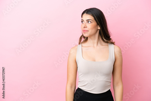 Young Italian woman isolated on pink background looking to the side