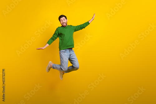 Full size cadre of crazy flying jumping shopaholic guy wearing denim jeans stylish outfit wings arms isolated on yellow color background
