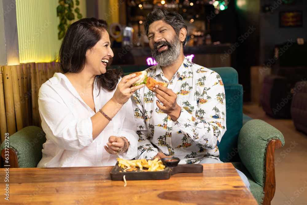 Indian Couple enjoying food and drink at restaurant.