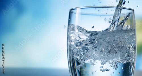 Pouring water into glass on blue background