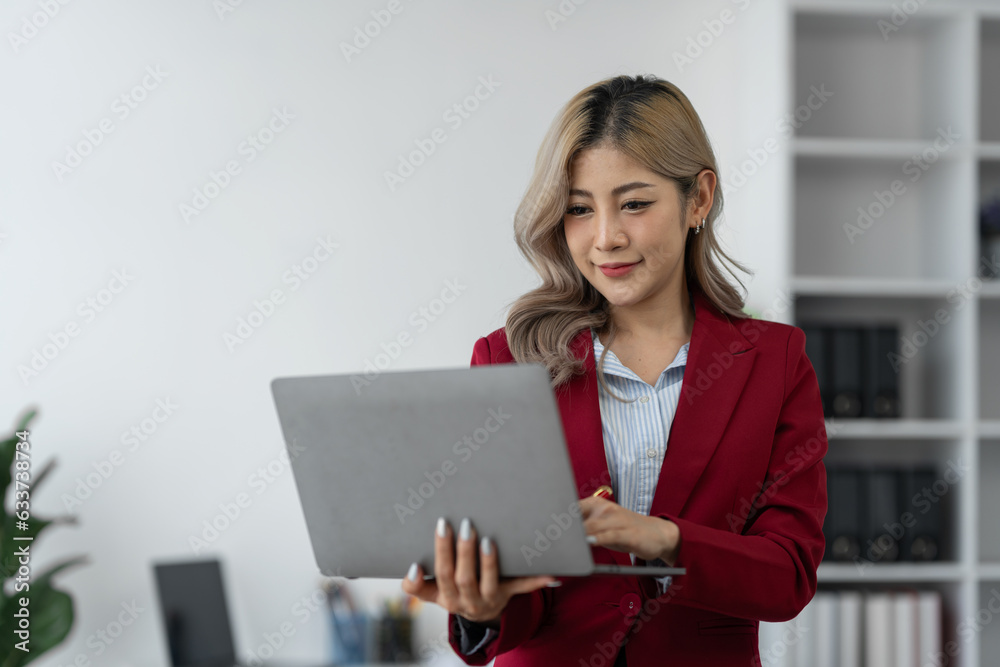 Portrait, Asian businesswoman or professional and confident female manager in standing suit holding a laptop computer to work, contact, search for business information online in the office