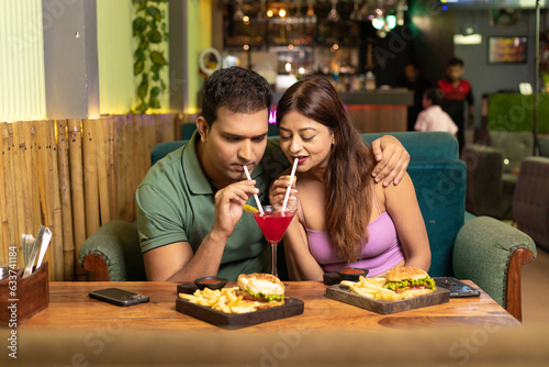 Indian Couple enjoying food and drink at restaurant.