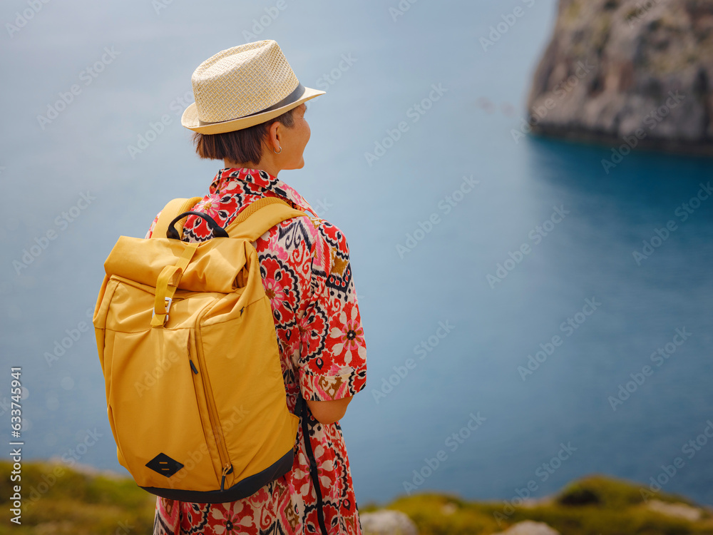 Asian woman in hat look on views of azure Bay in Mediterranean sea. Travel and vacation concept. Anthony Quinn bay with crystal clear water in Rhodes island, Greece. The most beautiful beach.