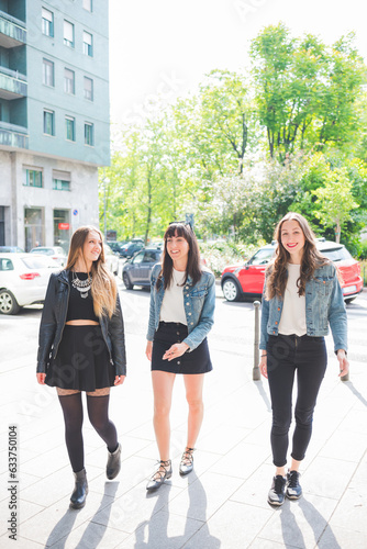 Three young happy women friends walking outdoors having fun