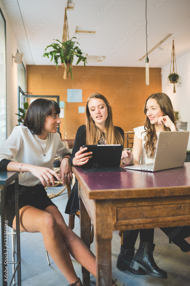 Three young beautiful caucasian millennials women indoor using computer discussing