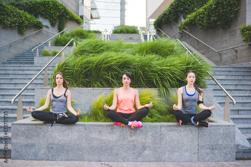 three young sportive women doing yoga outdoors