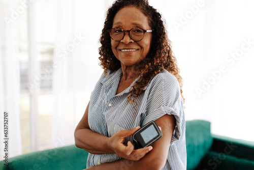 Woman checking her blood sugar levels with continuous glucose monitoring photo