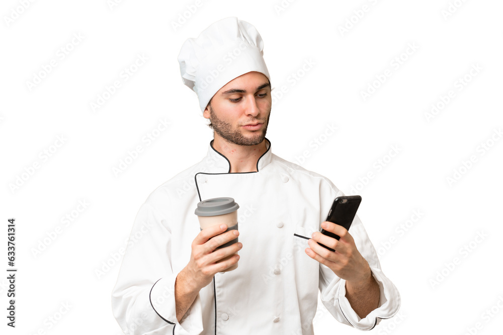 Young handsome chef man over isolated background holding coffee to take away and a mobile Young handsome chef man over isolated background holding coffee to take away and a mobile