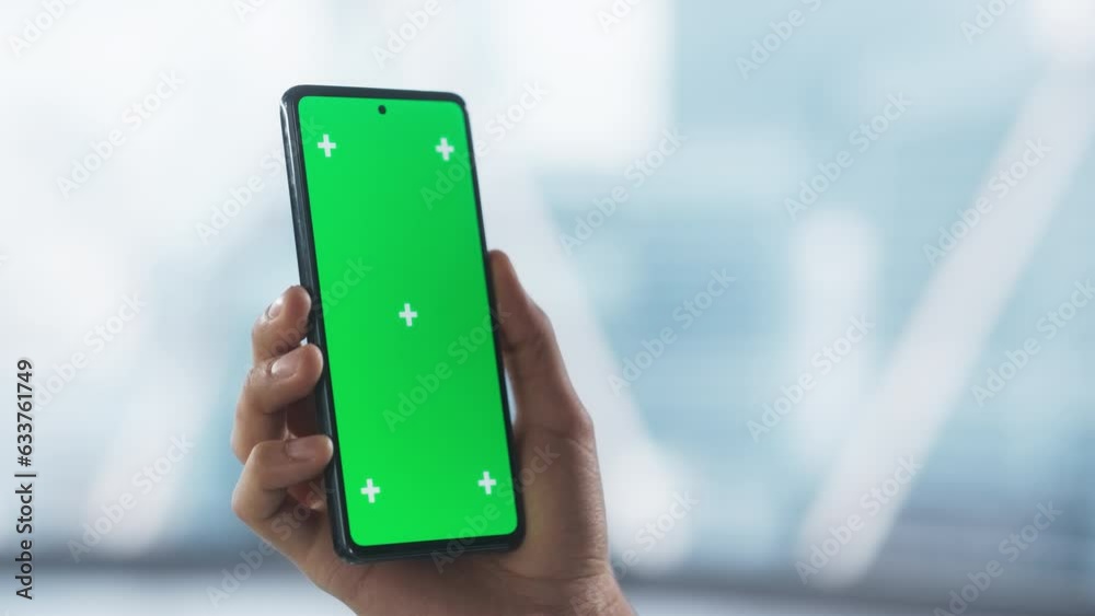 Entrepreneur Holding a Modern Mobile Phone in Front of a Camera. Smartphone with Green Screen Chroma Key Template for Digital Marketing, Promotion of Online Services, App, Software, Media Campaigns