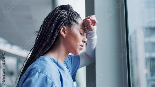 Woman, doctor and headache in stress, burnout or mistake leaning on window in hospital building. Frustrated or sad female person or medical healthcare nurse in grief, loss or failed surgery at clinic