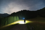 Night scene, the silhouette of a man with a headlamp goes hiking in the Tatra Mountains in summer.