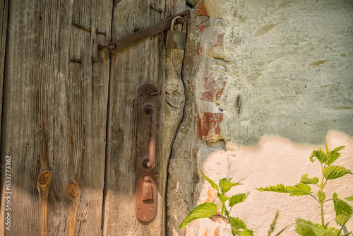 An old wooden door and iron bolt on an old old wall in the countryside. retro vintage details. Lifestyle.