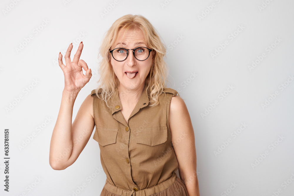 Portrait of adult woman showing OK sign with fingers isolated on white background. Successful career, accepted concept Portrait of adult woman showing OK sign with fingers isolated on white background. Successful career, accepted concept
