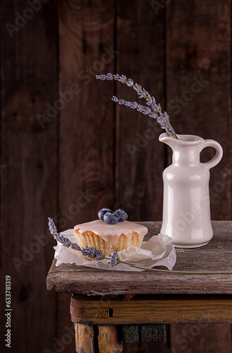 Muffin with bluberry decorated with lavender on rustic old wooden bench against of dark background © twomeerkats