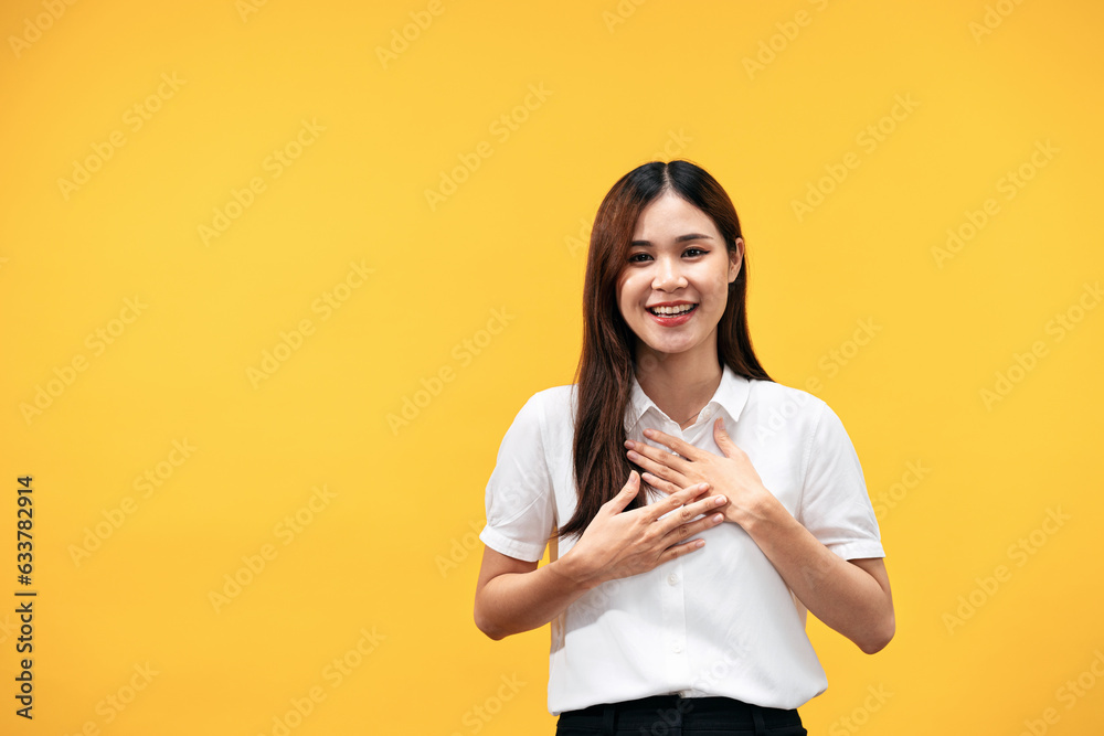 Young asian woman wearing white short sleeve shirt and places both hands on her chest while grateful Young asian woman wearing white short sleeve shirt and places both hands on her chest while grateful