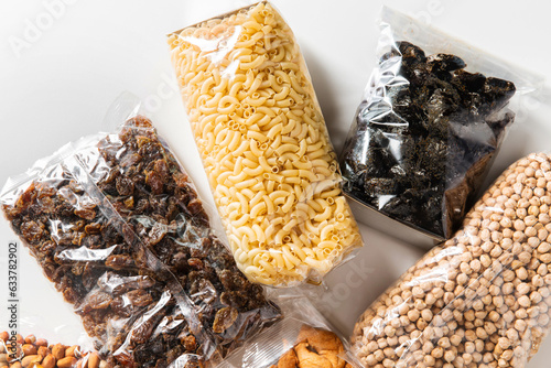 food storage, healthy eating and diet concept - close up of bags with dried fruits, cereals, pasta and nuts on white background
