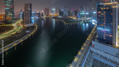 Cityscape of skyscrapers in Dubai Business Bay with water canal aerial all night timelapse