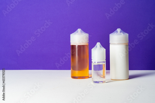 Electronic cigarettes liquid bottles on purple background